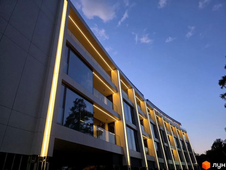 Emily Apartments - новобудова з панорамними вікнами та підсвіткою фасаду. Зовнішній вигляд будинку з балконами та скляними огорожами.