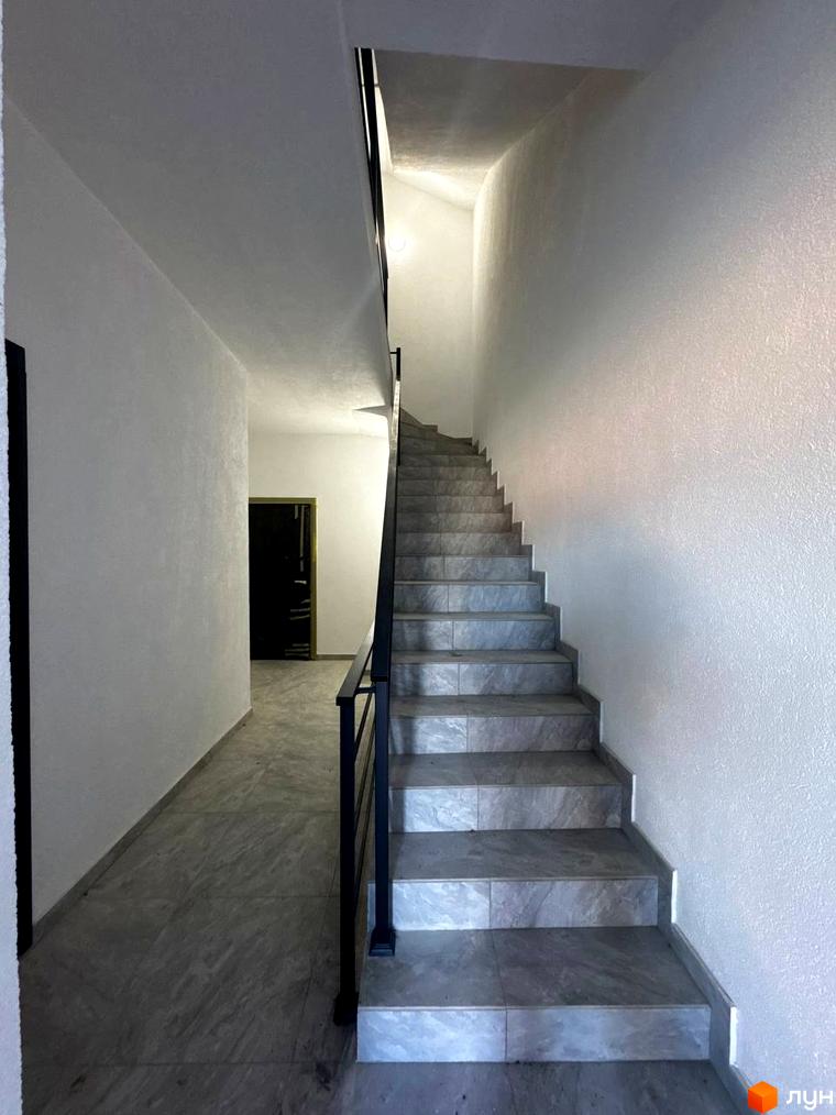 Вхідна група в житловому комплексі Затишок з мармуровими сходами та білими стінами. Просторий коридор веде до дверей.