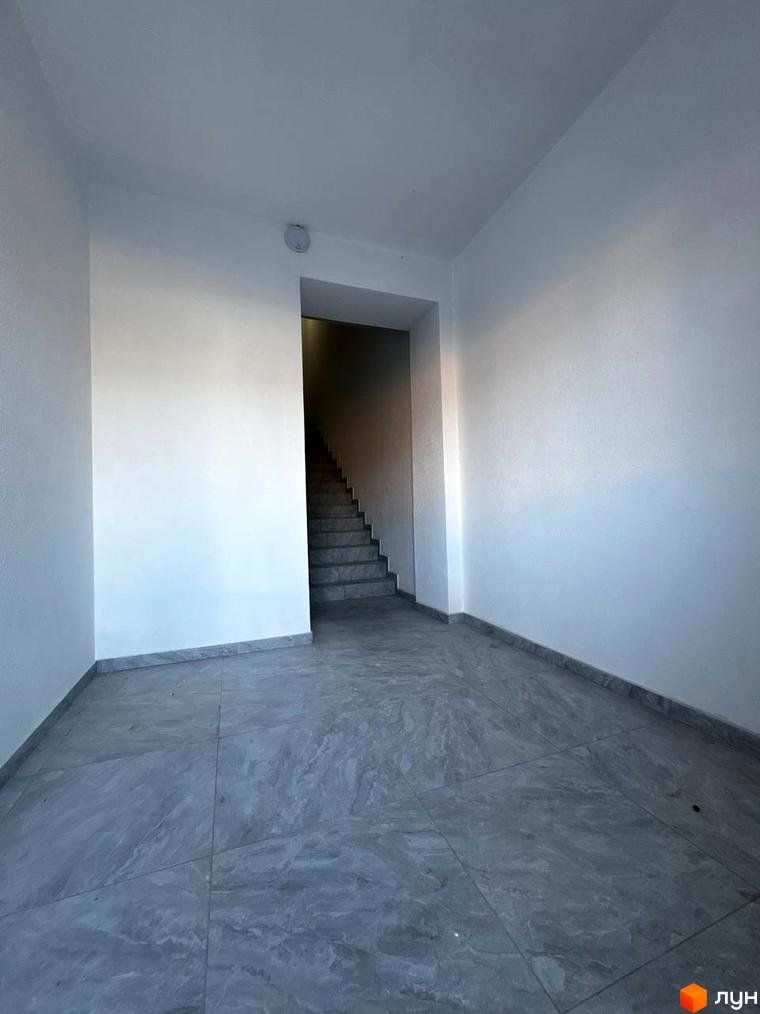 Фото сходової клітки в новобудові ЖК Затишок. Сіра плитка на підлозі та сходах, білі стіни.