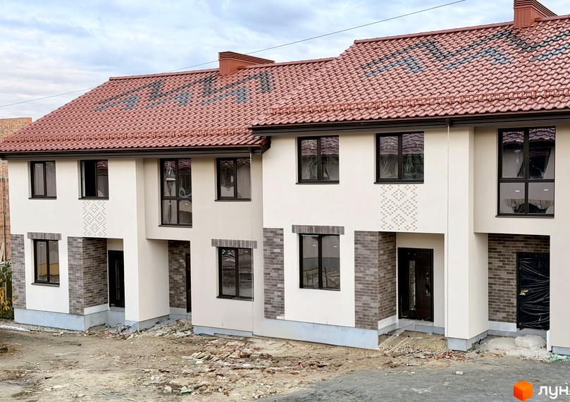 Котеджне містечко КМ Етнія: фасади будинків з червоною черепицею та цегляним оздобленням, навколо будівельний майданчик.