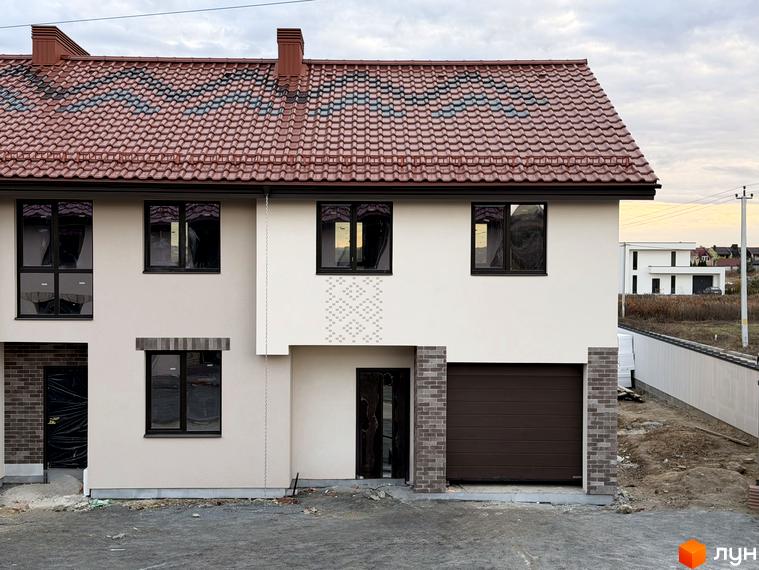 Котеджне містечко КМ Етнія: фасади двоповерхових будинків з червоною черепицею та гаражними воротами. Територія навколо будинків в процесі облаштування.