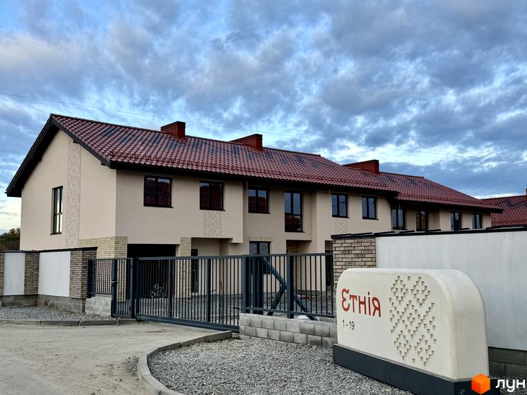 Котеджне містечко Етнія: фасади будинків з червоною черепицею та цегляними елементами, огороджена територія з воротами.