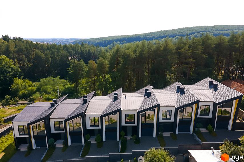 Таунхаус ДЖЕРЕЛЬНА: ряд сучасних триповерхових будинків з асиметричними дахами та великими вікнами, розташованих серед зелених насаджень.