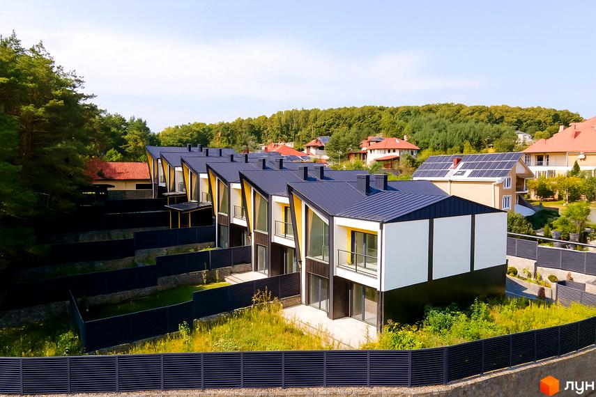 Таунхаус ДЖЕРЕЛЬНА - сучасний житловий комплекс з двоповерховими будинками та індивідуальними ділянками. Навколо комплексу зелені насадження та огороджена територія.