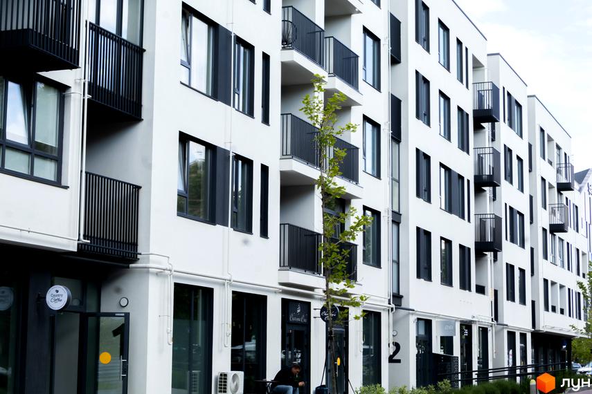 Житловий комплекс Empatika - це сучасна новобудова з балконами та великими вікнами. Територія перед будинком доглянута, з деревами та місцями для відпочинку.