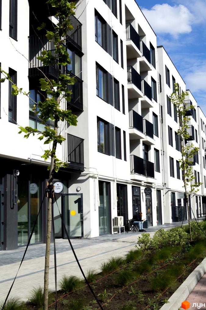 Зовнішній вигляд новобудови ЖК Empatika з балконами та вікнами, прибудинкова територія з деревами та зеленню.