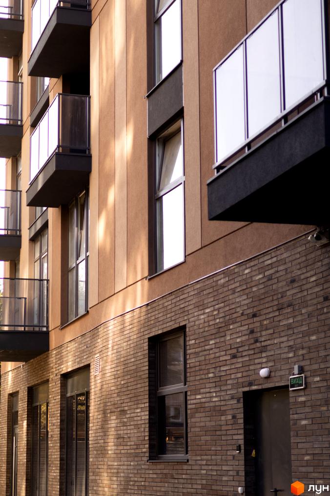 Фасад житлового комплексу Pokrovsky Apart Complex з цегляною обробкою та балконами. Зовнішній вигляд будинку.