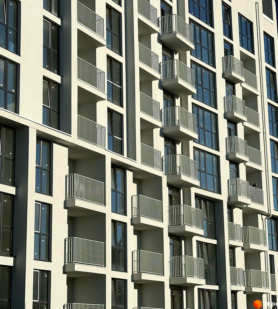 Зовнішній вигляд новобудови Pokrovsky Apart Complex з балконами та великими вікнами. Фасад будинку світлий, з чіткими геометричними формами.