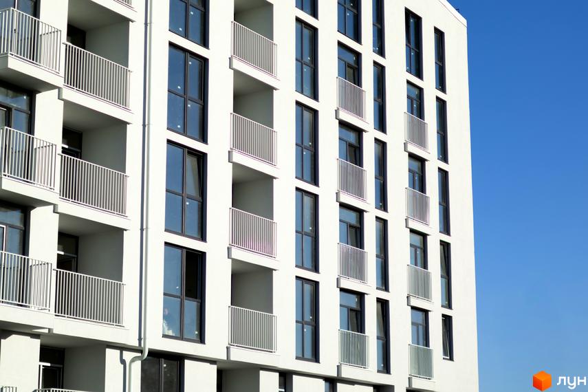 Фасад будинку житлового комплексу Pokrovsky Apart Complex з балконами та вікнами на тлі блакитного неба.