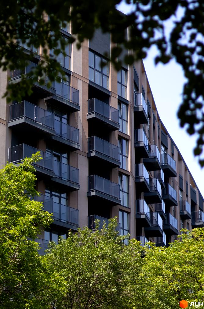 Pokrovsky Apart Complex - фасади будівель з балконами та вікнами, оточені зеленню дерев. Сучасна архітектура житлового комплексу.