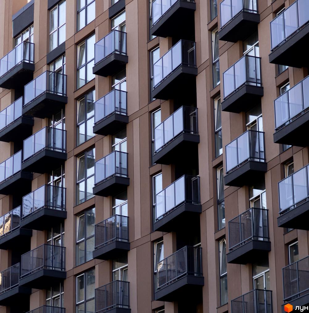 Зовнішній вигляд будинку Pokrovsky Apart Complex з балконами та вікнами. Фасад будівлі коричневого кольору.