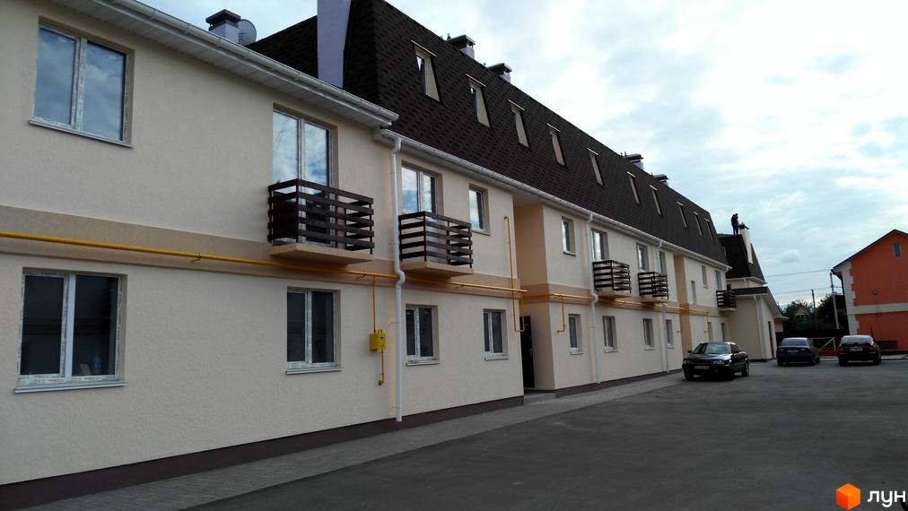 Зовнішній вигляд таунхаусів «Приват квартал» з балконами та вікнами. На території комплексу є парковка для автомобілів.