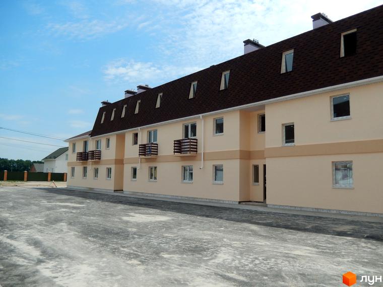 Зовнішній вигляд таунхаусів у житловому комплексі Private Quarter. Будинки з мансардним дахом та балконами, перед будинками асфальтований майданчик.