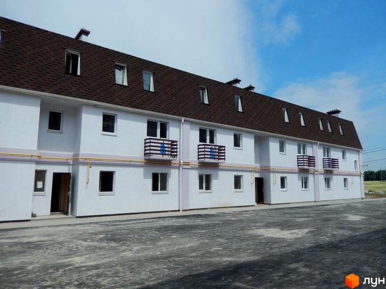 Зображення таунхаусів житлового комплексу Private Quarter. Білі будинки з коричневим дахом та балконами. Перед будинками асфальтована територія.