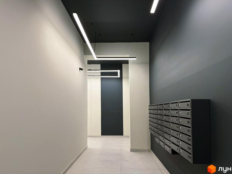 Вхідна група в новобудові ЖК Стандарт з індивідуальними поштовими скриньками та сучасним освітленням. Оздоблення стін та стелі виконано в нейтральних тонах.