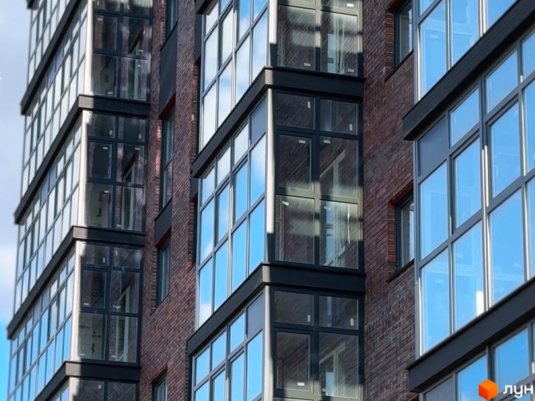Фасад житлового комплексу Стандарт з цегляним оздобленням та великими вікнами. Сучасна архітектура новобудови.