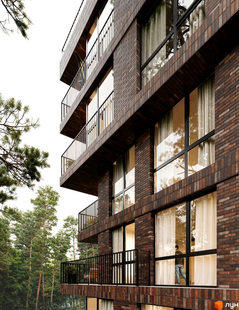 Житловий комплекс Astrid: фасад з темної цегли, великі вікна та балкони з чорними поручнями. Навколо будинку зелені дерева та сосни.