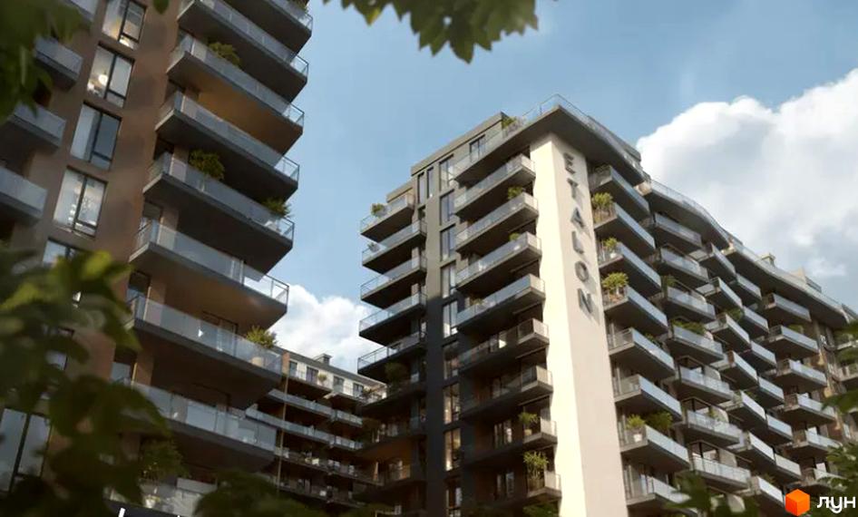 Новобудова ЖК Etalon Gold з балконами та скляними огородженнями. Зовнішній вигляд будинку з деревами на передньому плані.