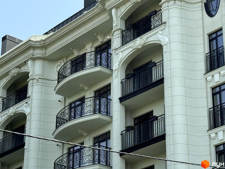 Зовнішній вигляд фасаду новобудови ЖК Гімназист з балконами та кованими елементами. Опис прибудинкової території відсутній.