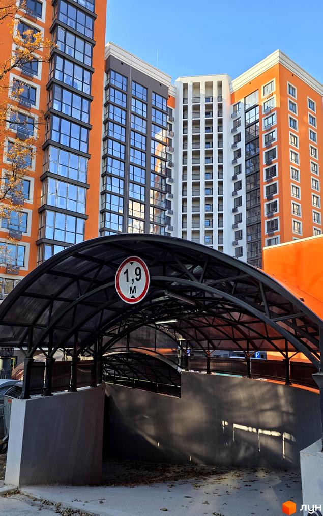 Новобудова Eco Dream з яскравими фасадами та скляними балконами, перед якою розташований навіс з обмеженням висоти 1,9 м.