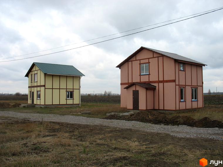Два двоповерхові будинки з вікнами та дверима на тлі похмурого неба. Поруч з будинками розташована прибудинкова територія з дорогою з гравію.