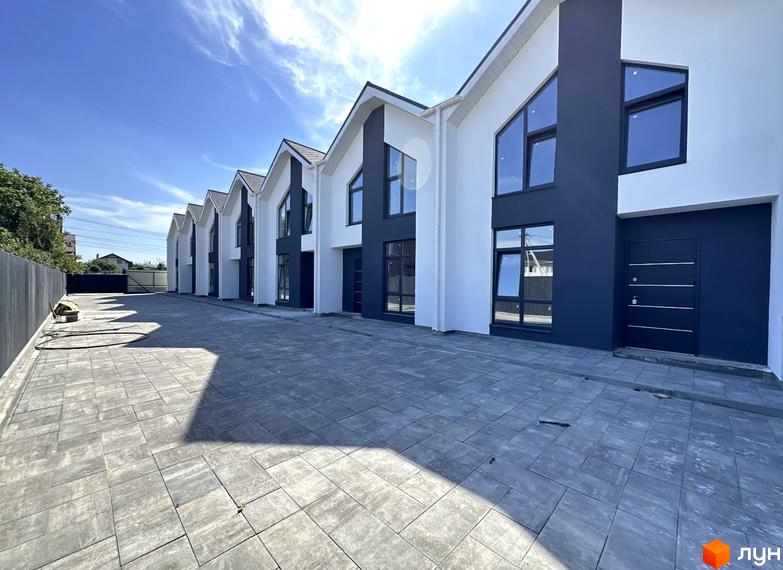 Зображення сторінки житлового комплексу. Таунхауси комфортного кварталу DeLuxe з білими стінами та темними вікнами, перед будинками викладена плитка.