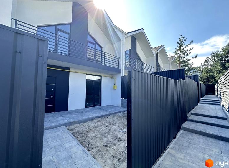 Зображення сторінки житлового комплексу. Білі будинки з темними акцентами та балконами, огороджені чорним парканом. Біля будинків викладена плитка.