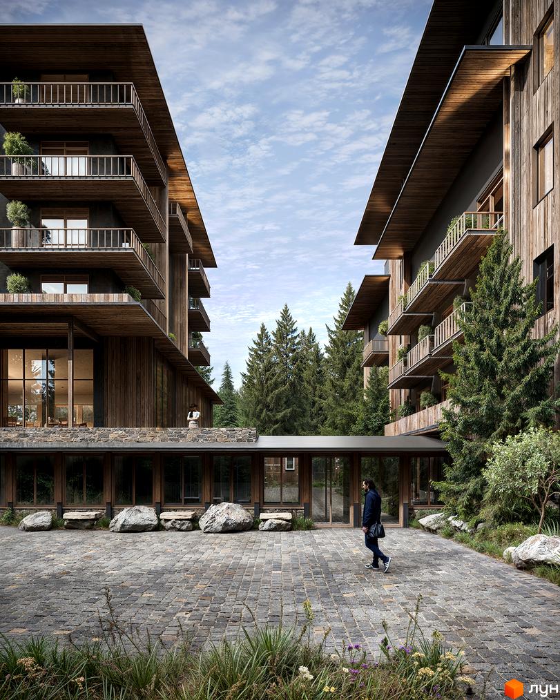 Зображення житлового комплексу з дерев'яними фасадами та балконами. На території комплексу бруківка, великі камені та зелені насадження.