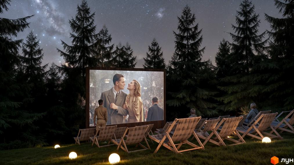 Вечірній кінопоказ у Містечку котеджів Вірші. На екрані романтична сцена, навколо ліс та затишні крісла для глядачів, а над головою зоряне небо.