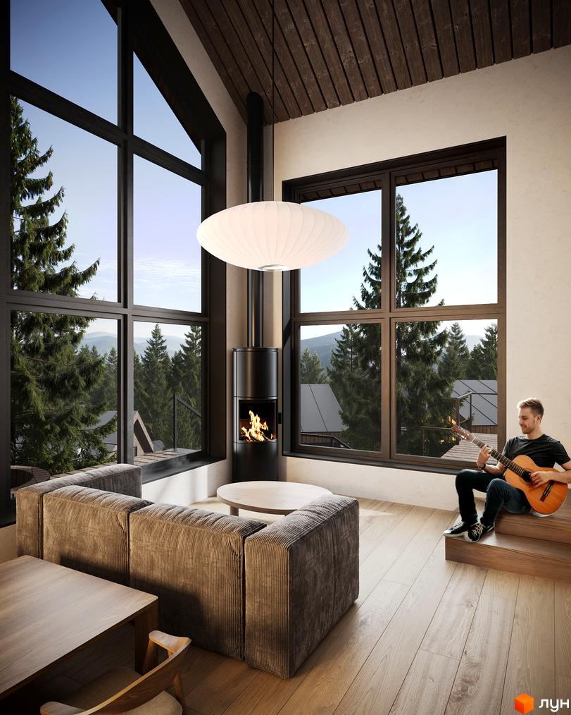 Затишна вітальня з великими вікнами та видом на гори. Чоловік грає на гітарі біля каміна, створюючи атмосферу спокою у Котеджне містечко Вірші.
