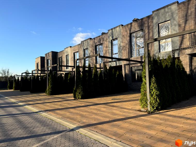 Зовнішній вигляд таунхаусів Eastville з цегляними фасадами та доглянутою прибудинковою територією з бруківкою та зеленими насадженнями.