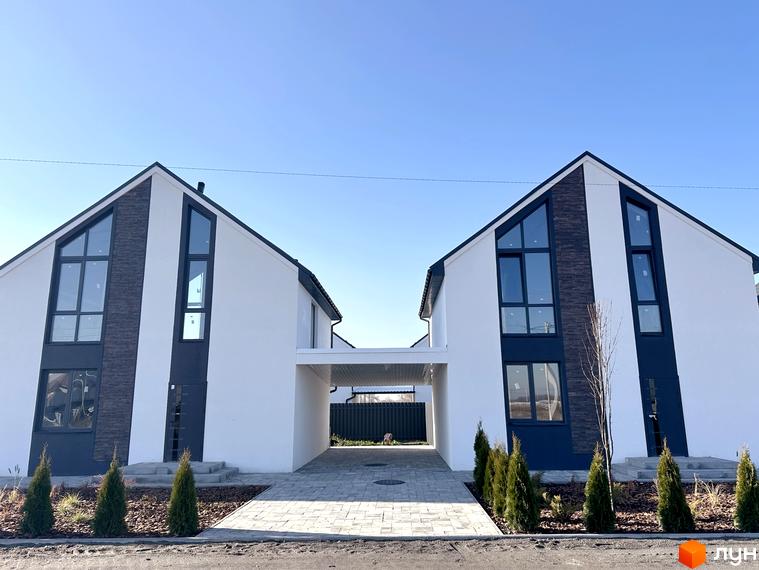 Два будинки з білими стінами та темними вікнами в Котеджному містечку DESNA HOMES. Передня частина з бруківкою та невеликими деревами.