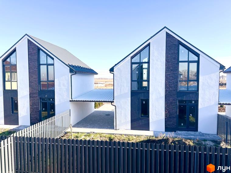 Два будинки в Котеджному містечку DESNA HOMES з білими стінами, великими вікнами та темною покрівлею. Перед будинками розташований паркан.