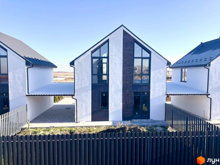 Фасад будинку в Котеджному містечку DESNA HOMES з великими вікнами та темним оздобленням. Перед будинком розташований паркан.