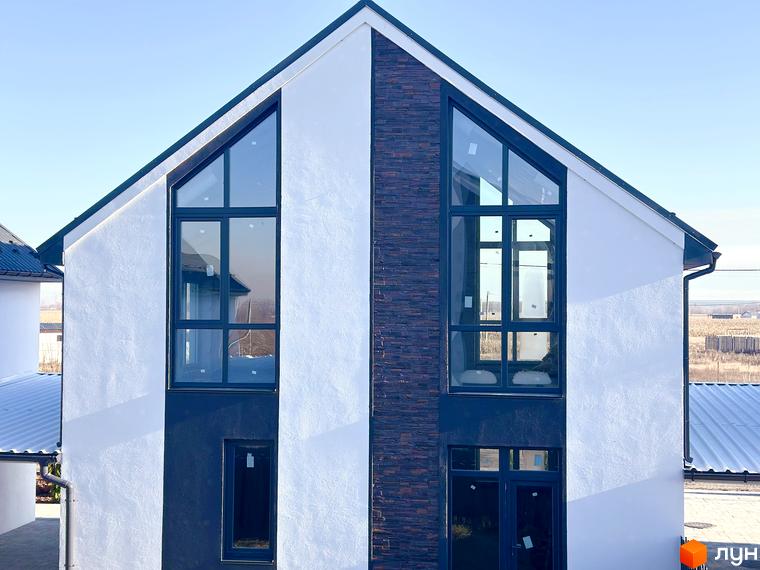 Фасад будинку в Котеджному містечку DESNA HOMES з великими вікнами та декоративною обробкою з каменю, блакитне небо на фоні.