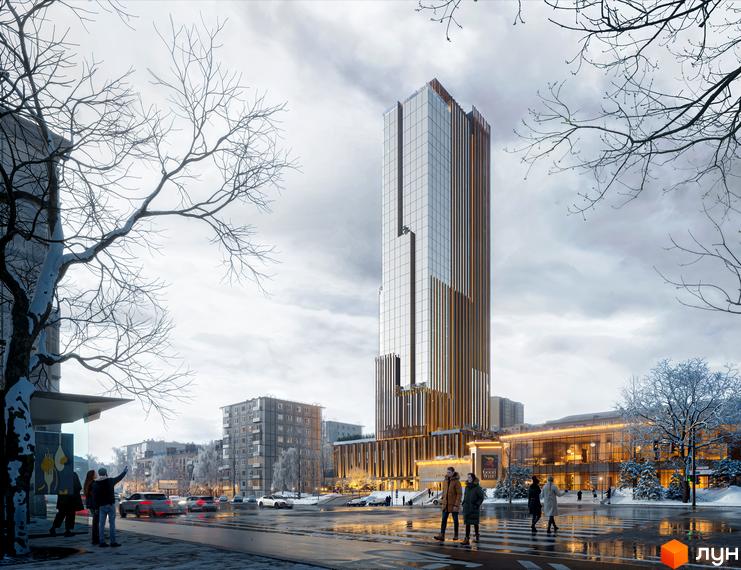 Зимовий вид на високий житловий комплекс THE ONE зі скляним фасадом та золотистими вертикальними смугами, оточений засніженими деревами та міською вулицею.