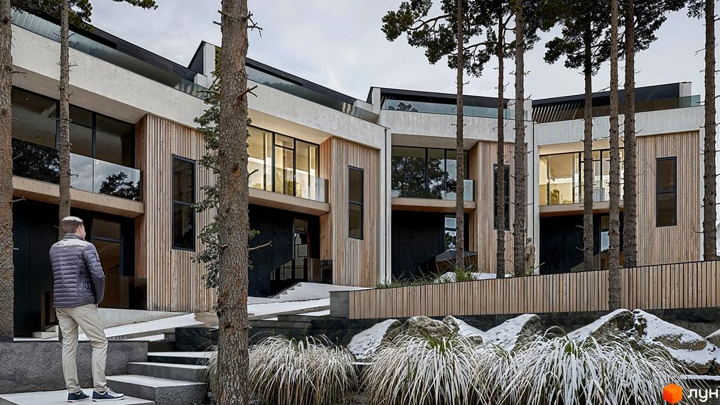 Багаторівневий будинок ZAGRAVA Villas & Residence з дерев'яним оздобленням та великими вікнами. Навколо будівлі ростуть високі дерева, а територія вкрита снігом та рослинністю.