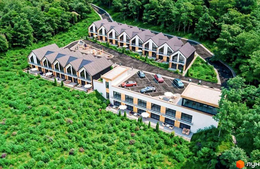 Аерофото Таунхауси River Stone: ряди будинків з гострими дахами, світлими фасадами та великими вікнами. На території є парковки, дитячий майданчик та багато зелені.