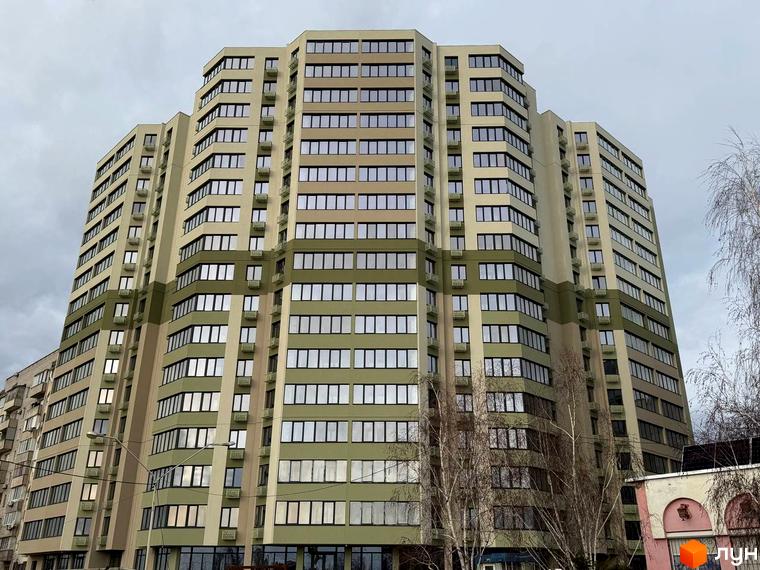 Багатоповерховий Житловий комплекс Граніт бежевого та оливкового кольорів з численними вікнами. На передньому плані видно голі дерева.