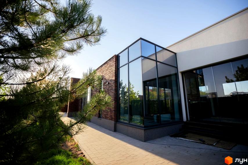 Котеджне містечко Comfort City GREEN PARK: будинок з цегляними та світлими стінами, великими скляними вікнами. Поруч викладена доріжка та зелені насадження.