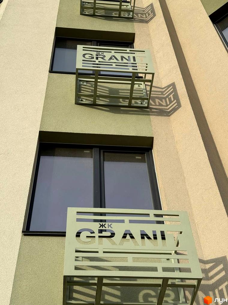 Фасад Житлового комплексу GRANIT з текстурованими стінами бежевого та світло-зеленого кольорів, темними вікнами та металевими декоративними панелями.