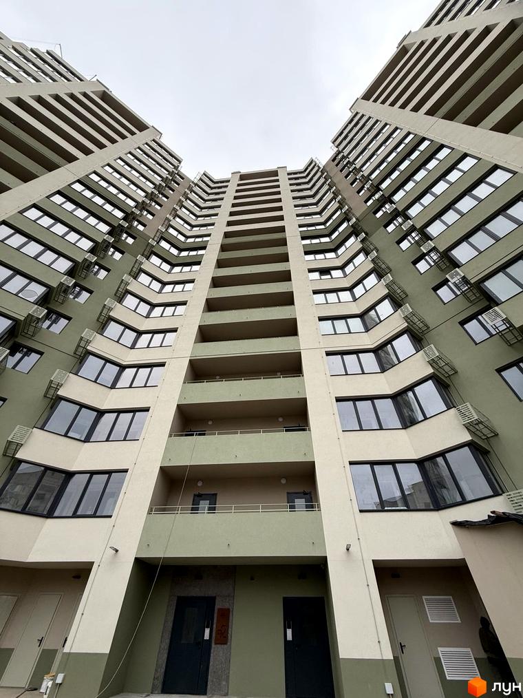 Житловий комплекс GRANIT: висотна будівля з фасадом світло-бежевого та оливкового кольорів, великими вікнами, балконами та зовнішніми кондиціонерами.