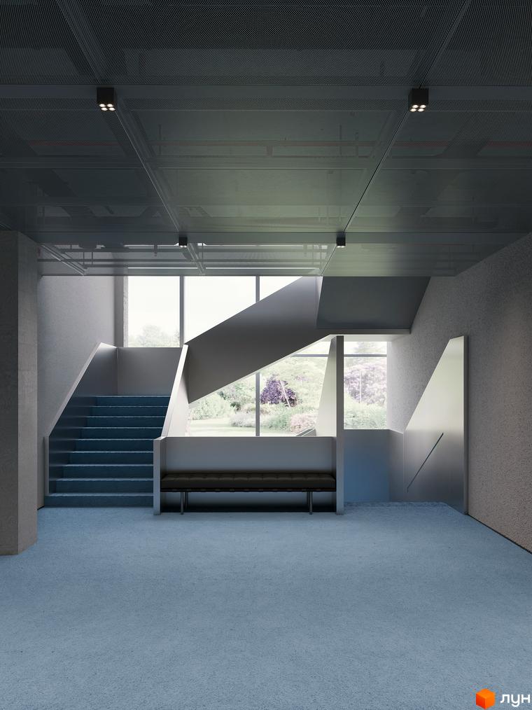 Інтер'єр холу Circle hotel&apartments з синім килимовим покриттям, геометричними сходами та великими вікнами, що виходять на зелений двір.