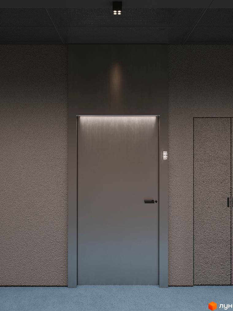 Вхід до апартаментів Circle hotel&apartments з темними стінами та дверима, освітлений точковими світильниками.