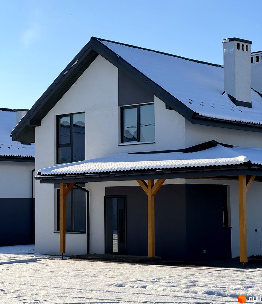 Котеджне містечко Буде Дім. Годовиця SPA. Двоповерховий будинок з білими стінами, темними акцентами та скатним дахом, вкритим снігом. Прибудинкова територія також засніжена.