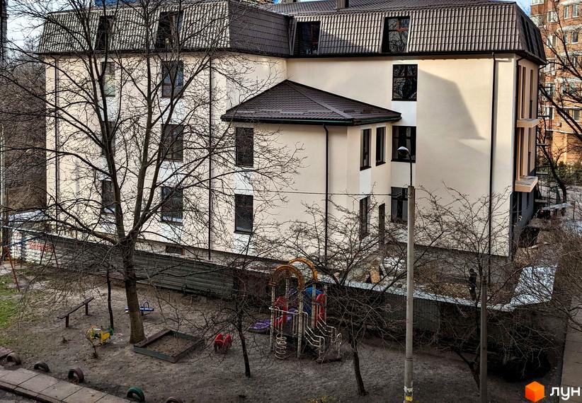 Житловий комплекс на вул. Яслинська, 3 з бежевим фасадом та коричневим дахом. На прибудинковій території розташований дитячий майданчик.