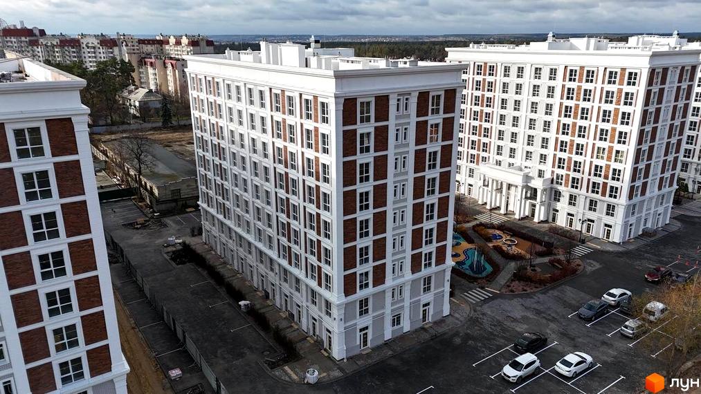 Вид на Житловий комплекс OXFORD: висотні будинки з білими стінами та цегляними вставками, облаштований двір з ігровим майданчиком та паркувальними місцями.