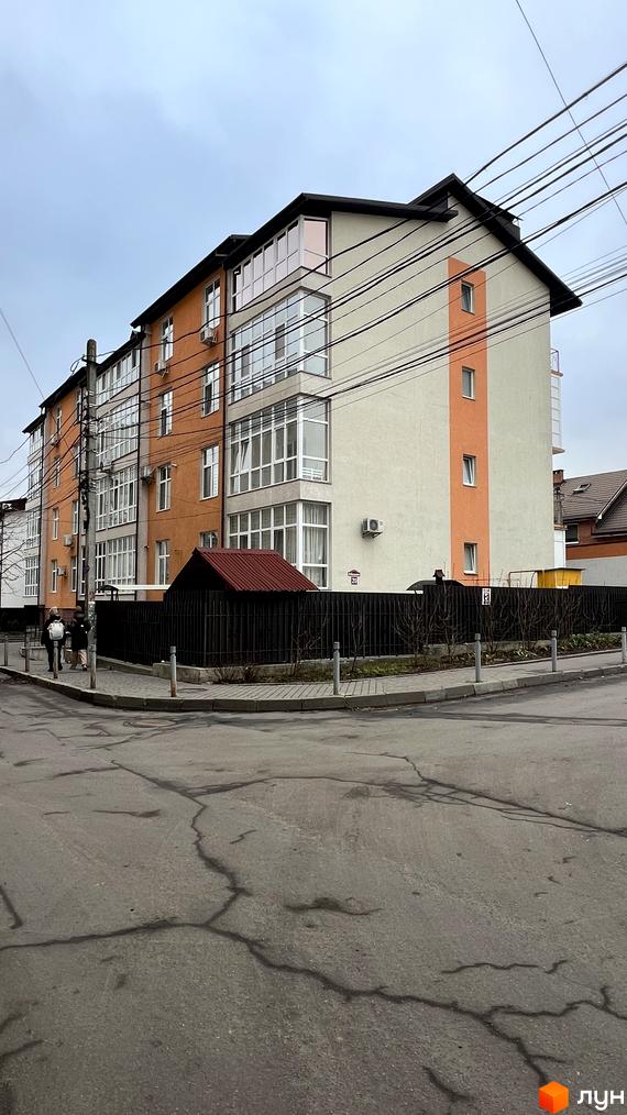 Будинок на вул. Заболотного, 20 з великими вікнами та сучасним фасадом. Прибудинкова територія з паркувальними місцями та огорожею.