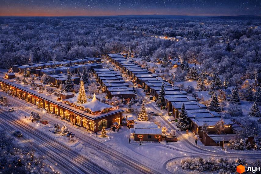 Котеджне містечко КМ Promin взимку, з новорічними прикрасами та освітленням. Засніжені дерева та будинки створюють святкову атмосферу.