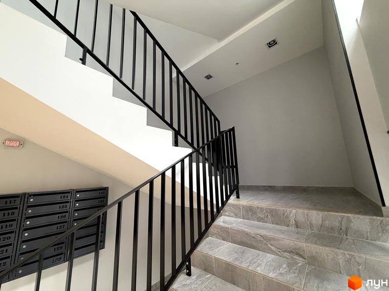 Сходи з чорними перилами у житловому комплексі Park Residence, з поштовими скриньками на стіні.